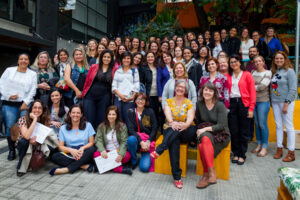 Foto em plano aberto de grande grupo de pessoas de diversas idades, reunidas ao ar livre. Elas sorriem e algumas estão segurando certificados nas mãos.