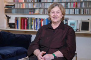 Elisabete França, uma senhora branca com cabelos curtos e claros, sentada e sorrindo na direção da câmera