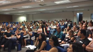 Auditório com educadores sentados durante formação.