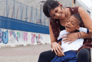 Professora abraça e interage com aluno com deficiência.