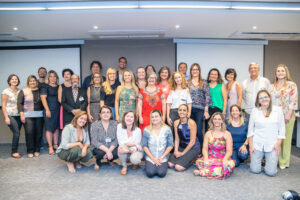 Homens e mulheres reunidos e enfileirados em um auditório, posando para foto.