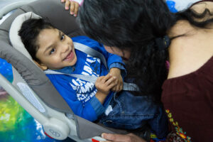 Menino com paralisia cerebral sorri enquanto interage com uma educadora