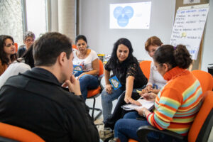 Grupo de professores, organizados em círculo, discutem e trabalham em grupo