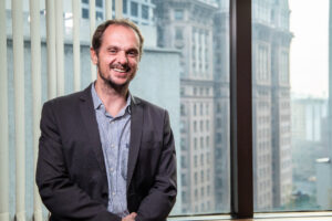 Foto de um homem branco, com barba e bigode, sorrindo.