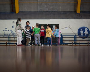Imagem de crianças numa quadra acompanhadas de professora.
