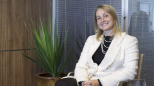 Foto da Daniela de Avilez Demôro sentada em um escritório. Ela está sorrindo.