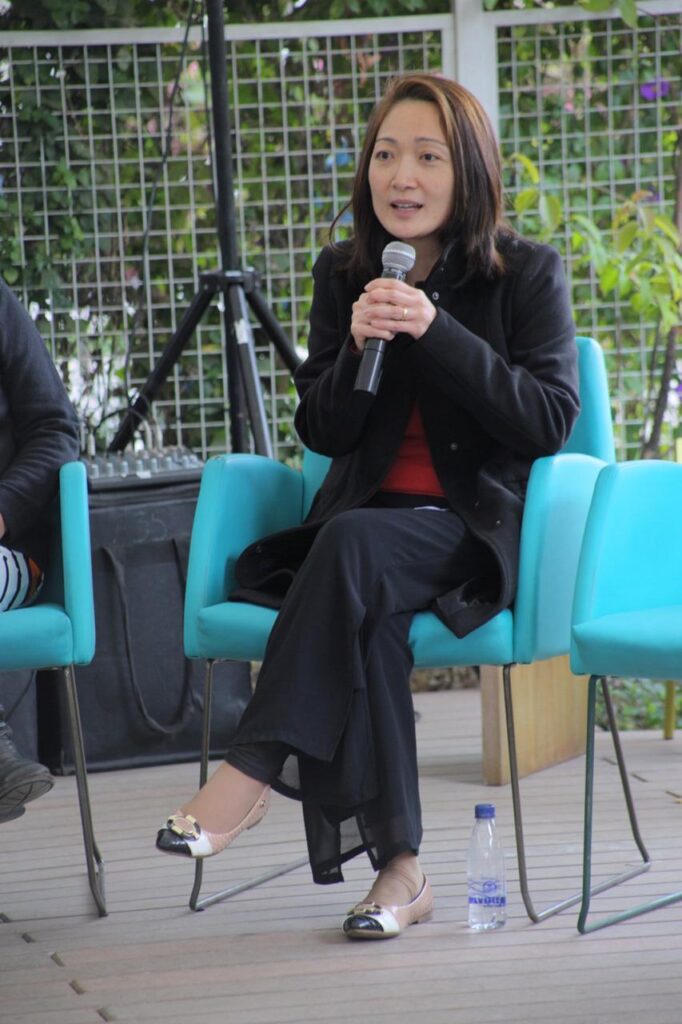Foto de uma mulher sentada falando ao microfone