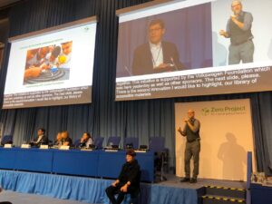 Foto de um homem cadeirante e mais três mulheres em uma mesa de debate. Há ainda um intérprete de Língua de Sinais.