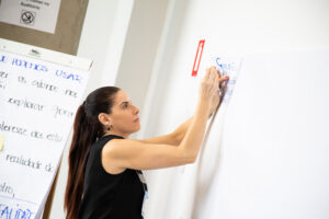 Foto de uma mulher colando uma folha em uma parede