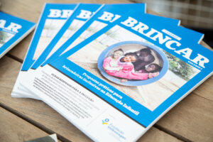 Foto de uma pilha de exemplares do Caderno Brincar em cima de uma mesa de madeira