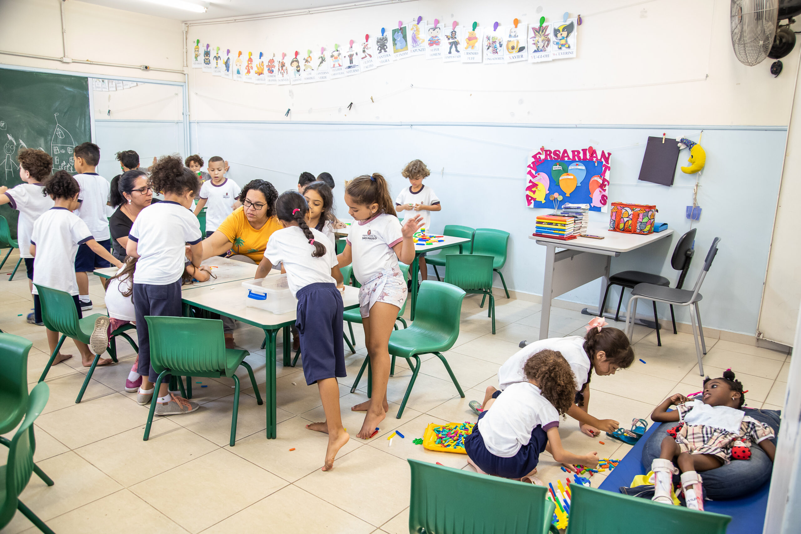 Foto de um grupo diverso de alunos com e sem deficiência em uma sala de aula