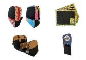 Foto de mochilas, conjunto de bolsas, jogos americanos e um porta celular, dispostos lado a lado, em um fundo branco.